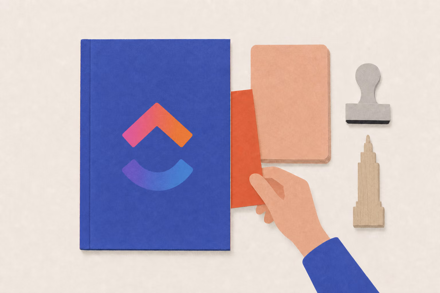 A hand tucks a bookmark into a setup binder beside a card stack, stamp, and tower-shaped paperweight